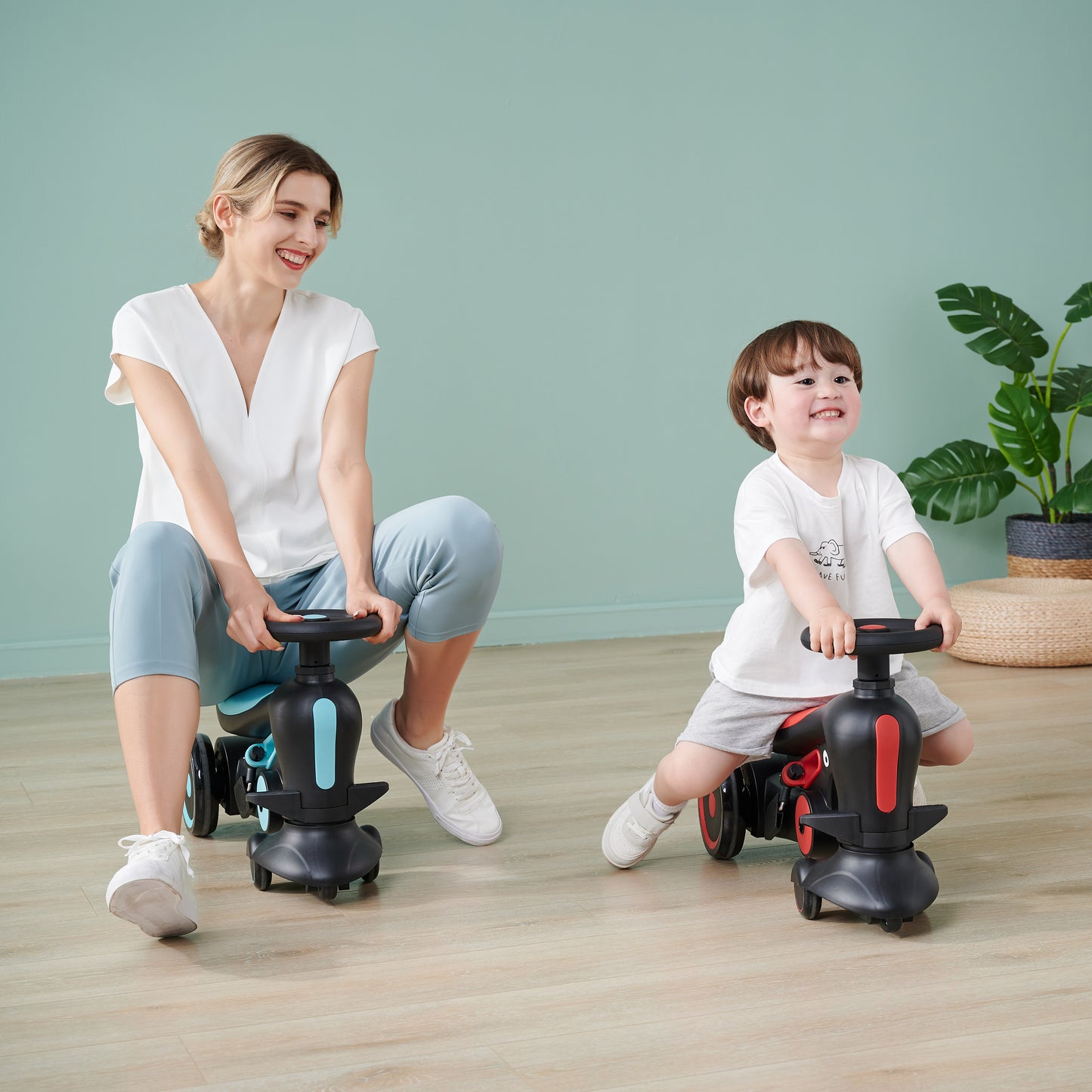 A woman and child sitting on toy vehicles, both smiling, in a bright indoor setting.