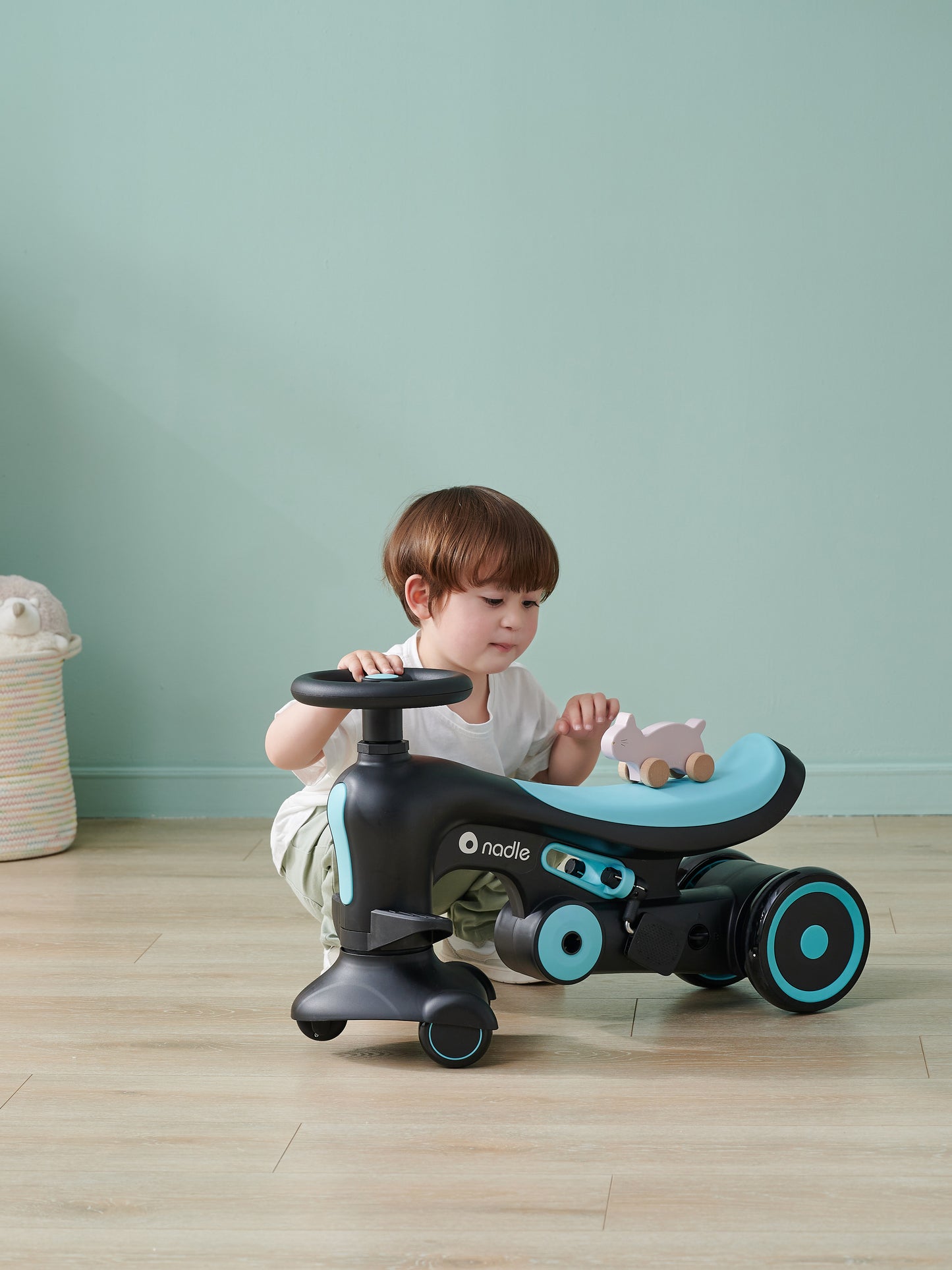A child plays with a toy car on a ride-on vehicle indoors.