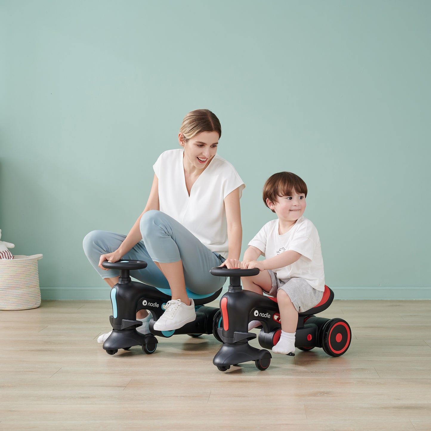 A woman and child happily riding on toy vehicles indoors, smiling at each other.