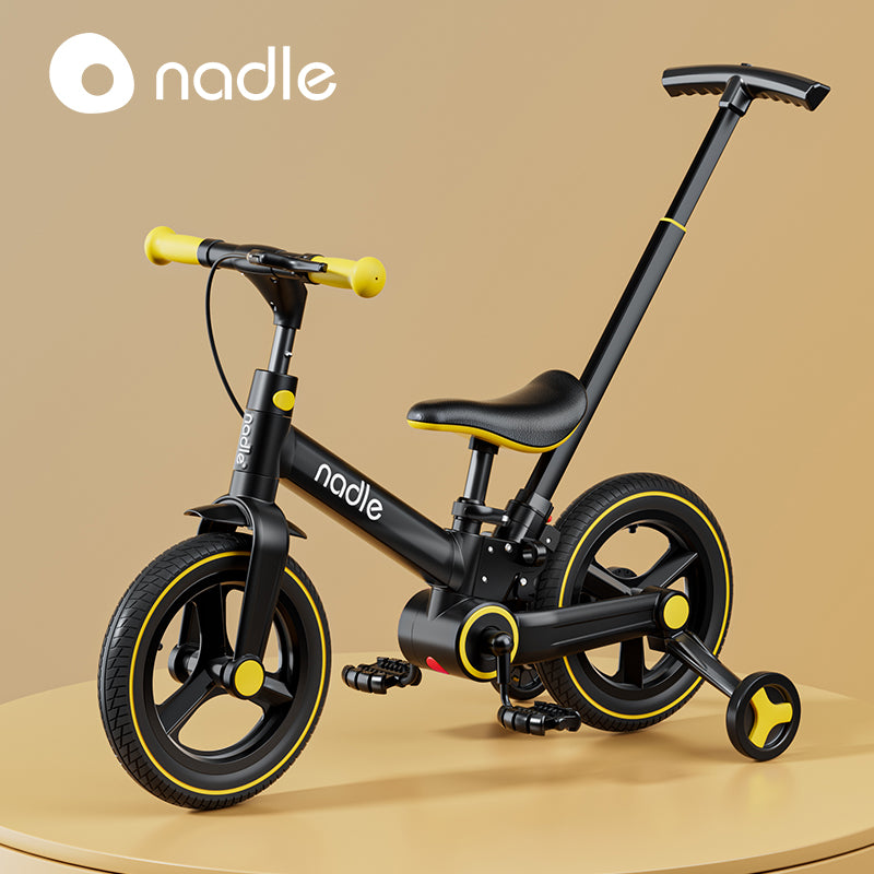 A sleek black and yellow children's bike with a push handle, displayed on a table.